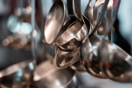 Silver spoons and steel tools in industrial kitchen. Gourmet restaurant before service, preparation and food processing concept. Master chef scene.