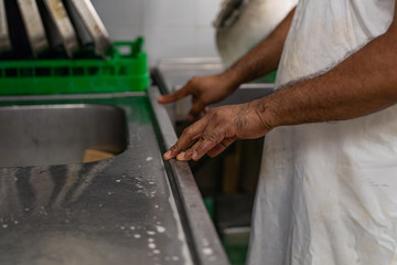 African and Syrian refugees working in a restaurant kitchen after a period of apprenticeship. Details of hands working and chopping.