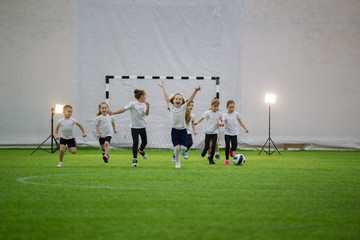 Little kids playing football indoors. Children football team running on the field