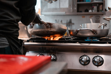 Young migrants working in Europe. Apprentice chef, job and occupation issues. Industrial restaurant kitchen details