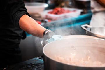 Steamy pot. Young migrants working in Europe. Apprentice chef, job and occupation issues. Industrial restaurant kitchen details
