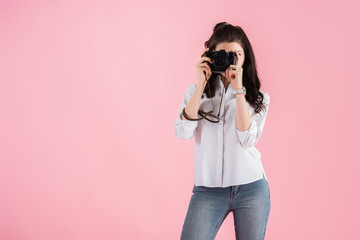 Studio shot of woman with digital camera taking photo isolated on pink