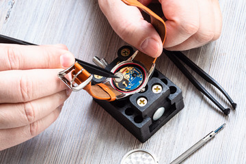 watchmaker removes battery from quartz wristwatch