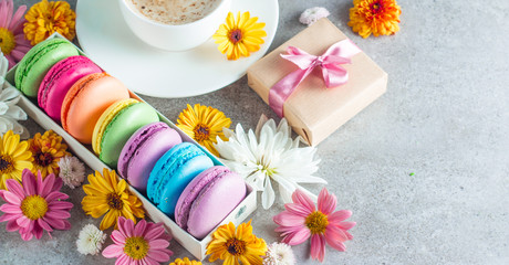 Photo of cake macarons, gift box, tea, coffee, cappuccino and flowers. Sweet romantic food macaroon concept. Morning breakfast and presents. Valentine's day concept.