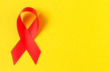 Red aids ribbon.  Isolated on yellow background with empty space for text.