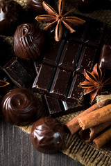 Assortment of dark, white and milk chocolate stack, chips. Chocolate and coffee beans on rustic wooden sacking background. Spices, cinnamon. Selective macro focus. Chocolates background. Sweets