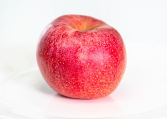 whole ripe red apple fruit on plate on white