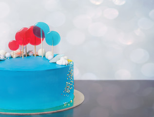 Blue buttercream Birthday cake with colorful lollipops.