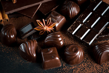 Assortment of dark, white and milk chocolate stack, chips. Chocolate and coffee beans on rustic wooden sacking background. Spices, cinnamon. Selective macro focus. Chocolates background. Sweets