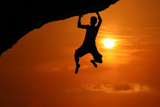 Silhouette of asian man climbing rock