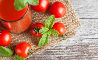 Close-up of a glass of tomato juice with vegetables on wooden sacking background. Vitamins and minerals. Healthy drink concept.