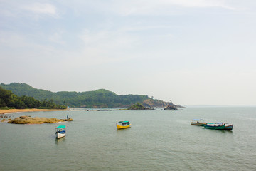 pleasure boats in the sea near the sandy beach and green hills jungle