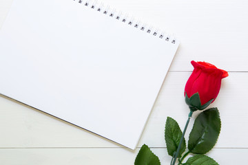 Present gift with red rose flower and notebook on wooden table, 14 February of love day with romantic, copy space with note or diary writing text for you, valentine holiday concept, top view.