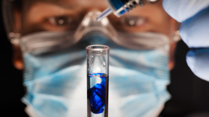 Laboratory worker scientist laboratory assistant tests chemicals for reactions in test tubes,...