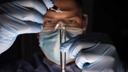 Laboratory worker scientist laboratory assistant tests chemicals for reactions in test tubes,...