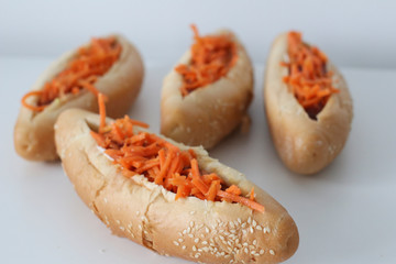 Incredibly delicious and juicy hotdogs with carrots on the white table. 