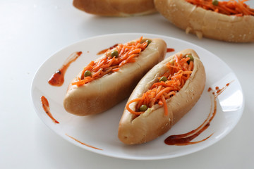Incredibly delicious and juicy hotdogs with carrots on the white table. 