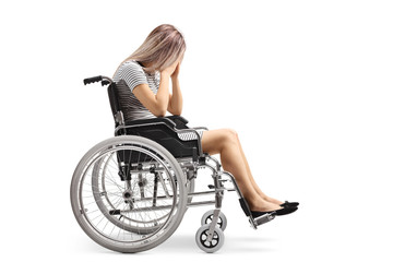 Fototapeta na wymiar Sad young disabled female in a wheelchair holding her head