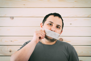 Angry man mouth covered by masking tape