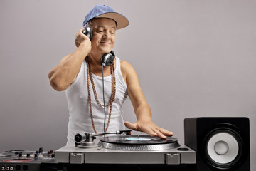 Senior dj with headphones playing music at a turntable