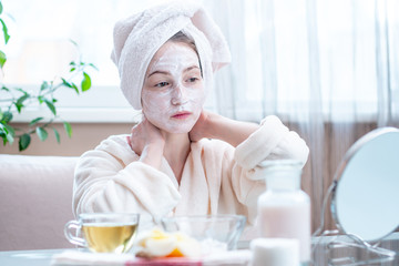 Obraz na płótnie Canvas Beautiful happy woman with cosmetic natural mask on her face looking at her skin. Skin care and Spa treatments at home