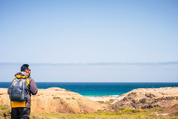 Lonely hiker backpacker man do trekking in tropical place with ocean and beach in background - enjoying nature and feel the freedom for people who love travel and lifestyle