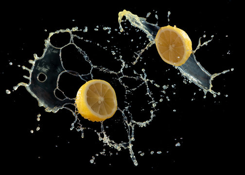 Lemom slice with juice splash isolated on black background
