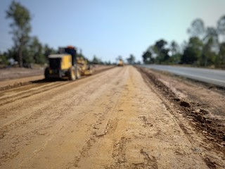 A landscape of construction site. There’s a tractor at the soil pile.