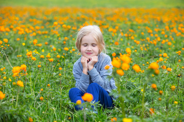Little cute baby girl is beautiful and happy, smiling in the summer in the meadow among the orange...