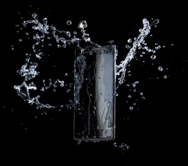 Smartphone with splashing of water or explosion flying in the air isolated on black background