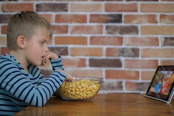 Young boy looking on a digital tablet with popcorn