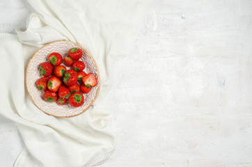 Fresh strawberries in a plate on a white tablecloth