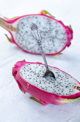 Two halves of dragon fruit with spoon on white background, tropical fruit
