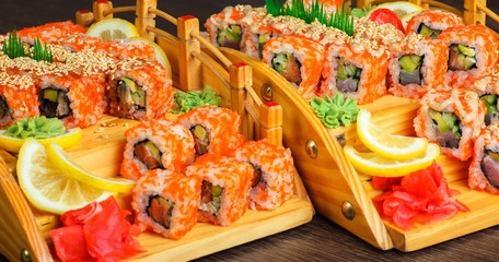 Red sushi sashimi set on a wooden bridge on a brown wooden table. With tune, prawn, shrimp, ginger, lemon