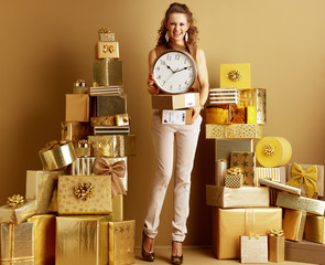 smiling stylish woman showing parcels and clock