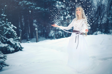 Winter Beauty Woman. Beautiful fashion model girl with snow hairstyle and makeup in the winter forest. Festive makeup and manicure. Winter Queen with snow and ice hairstyle