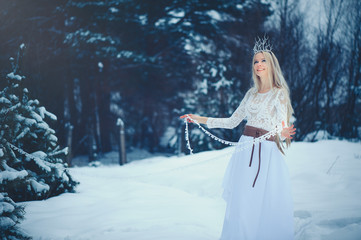 Winter Beauty Woman. Beautiful fashion model girl with snow hairstyle and makeup in the winter forest. Festive makeup and manicure. Winter Queen with snow and ice hairstyle