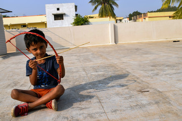Fototapeta na wymiar kid sitting on roof top and playing with bow and arrow