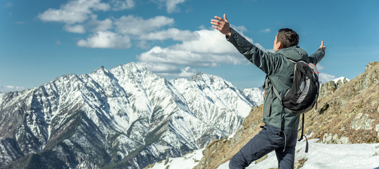 Men celebrate success by spreading their arms standing on background of snowy mountains....
