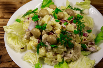 Potato salad with marinated mushrooms, eggs, red onion and mayonnaise on wooden table