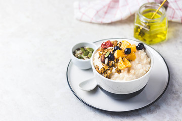 Rice porridge with berries, granola and honey. Selective focus, space for text.