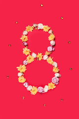 The conceptual composition from flowers about Eights march woman's day, holiday on a red background. The number 8 in decor. Top view