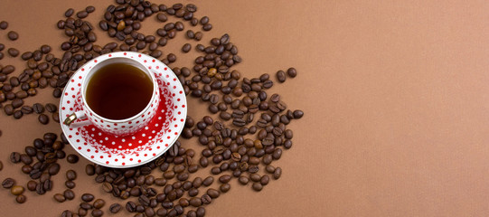 polka dot coffee cup and coffe beans mess on a brown background banner , place for text