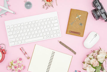 Flat lay pastel design of Valentines' day travel concept. Top view of blank notebook, wireless keyboard and mouse, passport, roses and camera on pink pastel color background. Travel in summer 