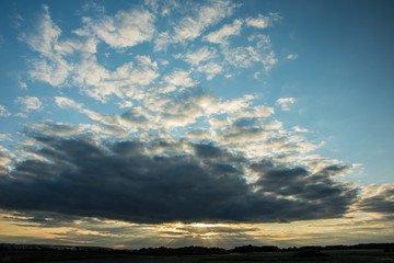 Gray evening clouds and sunbeams in the sky, horizon and tree