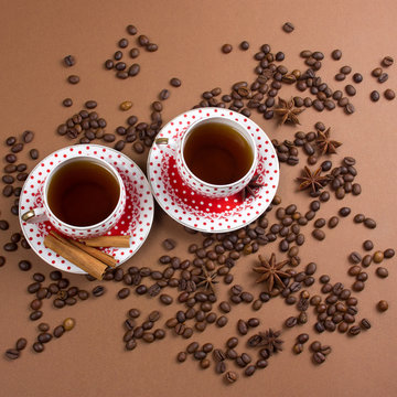 two spicy black coffee polka dot mugs and coffee beans mess on brown  background squae image