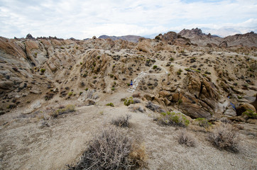 Woman hiker walks along a dirt trail through the Alabama Hills to the The Mobius Arch Loop Trailhead
