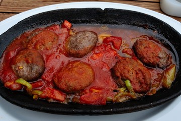 Turkish meatballs cooked in a tile pot with onion, tomato and pepper sauce - Kiremitte Kofte