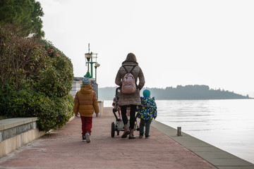 Obraz premium Young mother walking on a promenade along the sea pushing a stroller