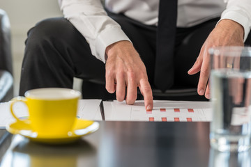 Fototapeta na wymiar Businessman sitting at a club table in his office reviewing statistical charts